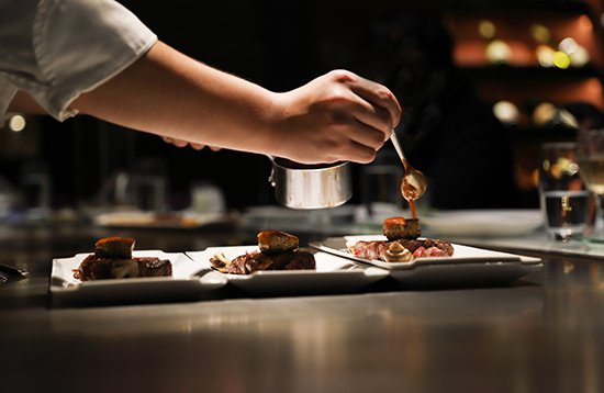 Chef plating dishes in the kitchen at Roth’s Sea & Steak
